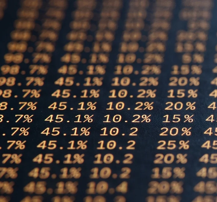 Rows of amber benchmark figures printed on a dark blue surface, one band in sharp focus, the rest falling away into blur.